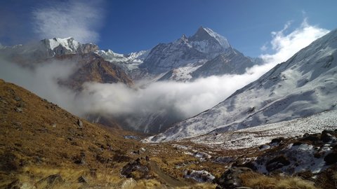Time lapse of clouds dramatically moving on the Annapurna base camp hiking trail with the majestic Machapuchare peak in the background in the Himalaya in Nepal