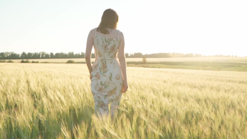 Girl in a dress in a wheat field at sunset