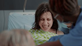 Close up of woman in painful labor giving birth to child in hospital ward. Caucasian person in agony getting assistance from doctor and african american nurse for baby delivery - Powered by Shutterstock - Get 15% off with code: PIKWIZARD15