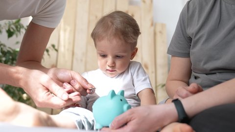 piggy bank. happy family a business concept. little son puts coins in piggy bank sits on the bed with parents. happy family collecting coins for save home business plan. happy family hoarding money