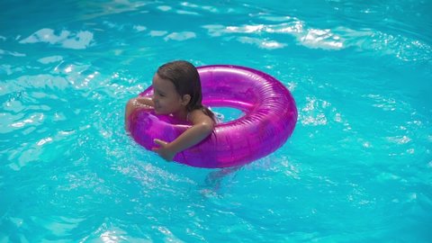 little girl jumps into an inflatable circle with a pool side. Children have fun and play, dives on the water pool in the swimming ring. Concept summer on vacation, holidays, weekends with kids
