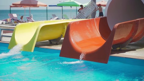 schoolgirl rolls down slide in water park. Summer holidays as a family in the water park. child on an inflatable circle slides along a water slide and dives into the pool