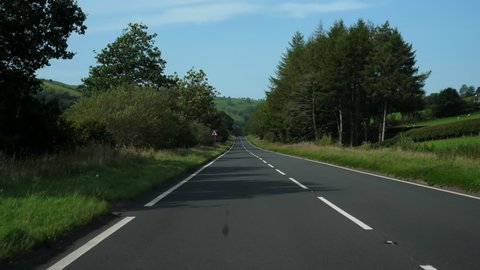 Car point of view, POV, driving down the hill stretch of road A40 in a beautiful English countryside scenery.