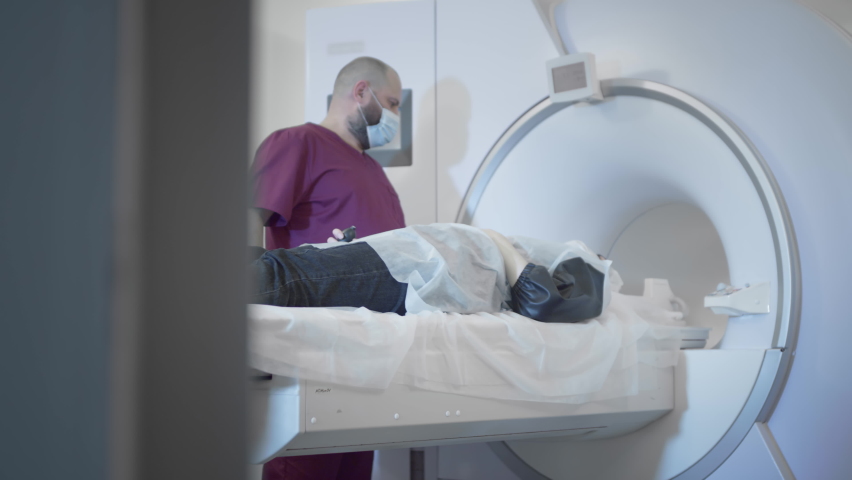 The doctor conducts an MRI or PET scan of a patient in a modern clinic. Girl on the bed inside a 3D scan machine. Magnetic resonance imaging in the study of the human body. The woman is doing CT scan Royalty-Free Stock Footage #1076579537