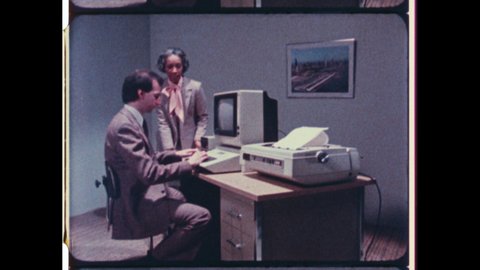 1980 Cupertino, CA. Woman dictates as Man types on Apple Macintosh Computer in Business Office. Close Up of Fingers  Typing on Keybaord. 4K Overscan of Vintage Archival 16mm Film Print