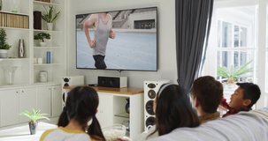 Composite of happy family sitting at home together watching athletics event on tv. sports, competition, entertainment and technology concept digitally generated video.