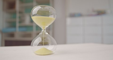 Hourglass or sandglass : Closeup of sand falling down through a narrow neck in a sand clock or sand timer. Indicating passing of time. Each hourglass measures and has specific duration of time.