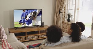 Composite of happy family sitting at home together watching baseball game on tv. sports, competition, entertainment and technology concept digitally generated video.