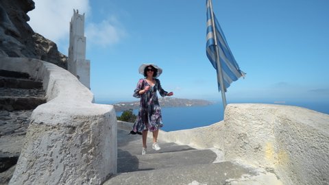 Woman in dress enjoy Santorini island on stairs at Heart of Santorini and Orthodox Church of Agios Nikolaos