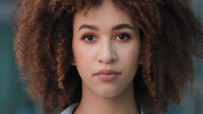 Extreme close-up female upset face head with stylish make-up afro hairstyle, outdoors portrait african american ethnic mixed race girl woman sad model serious frustrated expression looking at camera | Shutterstock HD Video #1076596682