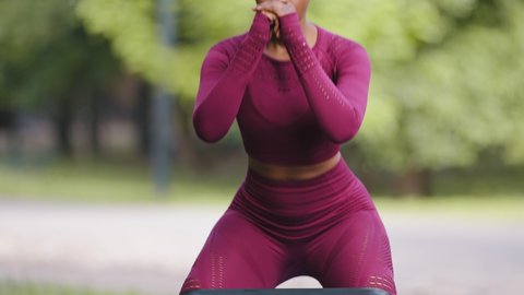 Closeup plus size sporty young woman doing squat morning exercise alone. Black African female fitness trainer wearing sportswear crouching training muscles workout for healthy body lifestyle concept