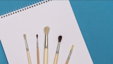 brushes and sketchbook on a blue background