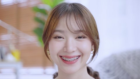 Asian woman with braces smiling until she sees wearing braces, beauty concept