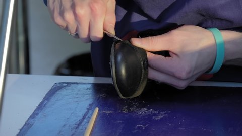 Shoemaker, shoes master using awl and repairing black leather women footwear at workshop - close up