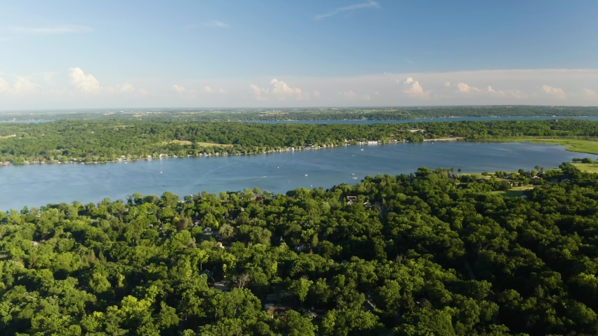 Aerial View, Large Blue Lake surrounded by Green Trees. Vacation Homes. Descend