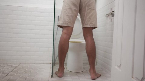a man peeing standing up in the restroom shoot from behind