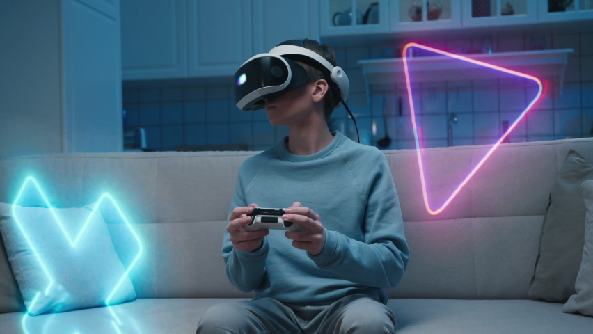 Person Uses Virtual Reality in Headset Gaming Interface. Boy Play Holographic Sitting in Home and Holding in Hand Gadget. Looking in Bright Interactivity Visual Screen Helmet. Industry Four Concept 4k Royalty-Free Stock Footage #1076617967