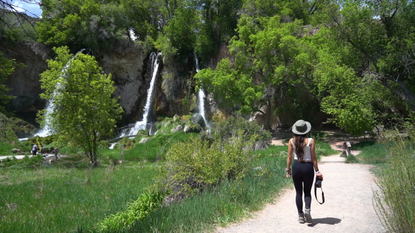 Back of Young Female Photographer Walking With Camera on Path Under Waterfalls. Riffle Falls State Park, Colorado USA, Full Frame Slow Motion
