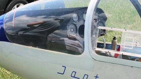Buzova, Kyiv, Ukraine - 07.07.2021 Glider pilots talking near airplane before flight, reflection in glass. Aircraft on the land. Jantar Standard fixed-wing plane without motor. Soaring sport