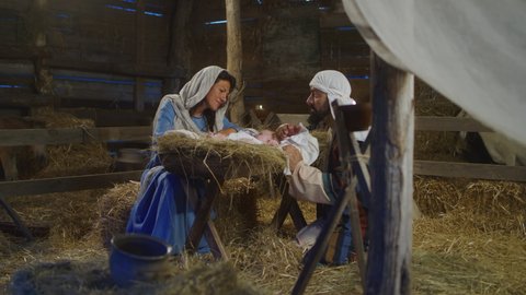 Virgin Mary and Joseph talking and taking care of baby Jesus Christ in manger on Christmas day in stable in Bethlehem