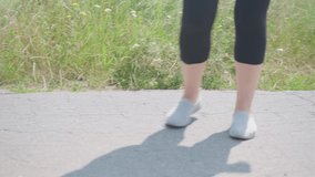 Close up video of the legs of the woman jogging early in the morning on the forest road, concept of a healthy lifestyle and keeping the body in shape.