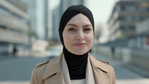 Portrat of attractive arabian business woman in hijab standing on street of big city looking into the camera. Successful and confident lady outdoors. Concept of business and career