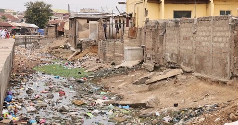 NIMA, GHANA - 20 JUL 2021: Muslim neighborhood poverty pollution homes Accra Ghana. West Africa. towns, villages communities polluted by trash, garbage and sewage. Plastic, industrial, sewer waste.
