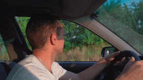 Cinematic inspiring video of young man traveling by car or camping, enjoying road and countryside, moving his hand in wind. It is illuminated by rays of the setting sun. he is joyful. slow motion.