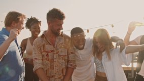 Slowmo handheld shot of happy young people partying on rooftop terrace on nice summer evening. They are dancing and laughing - Powered by Shutterstock - Get 15% off with code: PIKWIZARD15