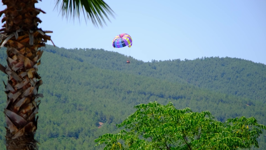 Tourists parasailing fly to the ocean shore, tourist season and travel concept. Antalya, Turkey. Flying with parachute