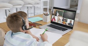 Schoolboy using laptop for online lesson at home, with diverse teacher and class on screen. communication technology and online elementary education concept, digital composite video.
