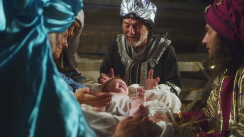 Nativity shot of Wise Men talking with Mary and Joseph over manger with baby Jesus Christ on Christmas Day in Bethlehem