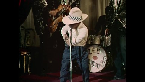 1964 - In this exploitation movie, a little person is the front man for a band and does singing impersonations.