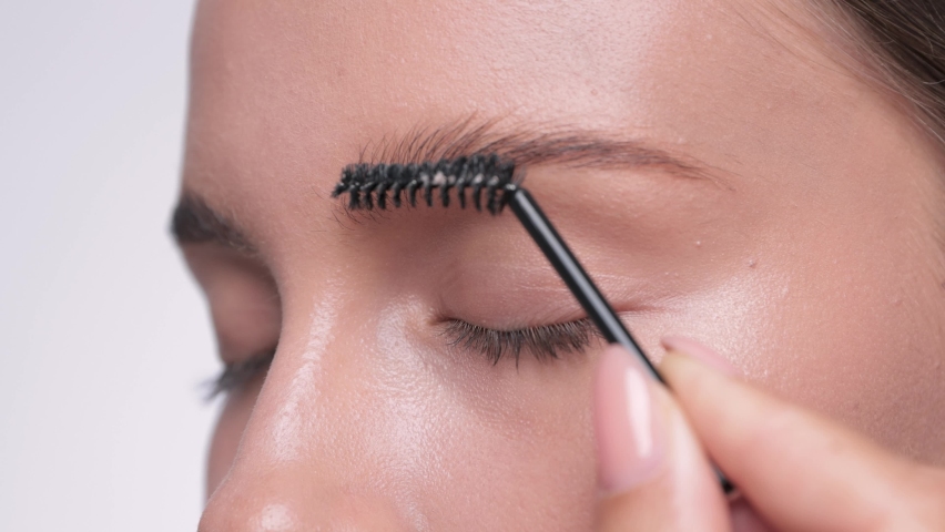 The make-up artist combs the eyebrows and makes the styling of the eyebrows with a gel. 
 Professional makeup and facial care. | Shutterstock HD Video #1076662337