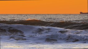 Golden sunrise over the sea. Ocean waves flood the beach