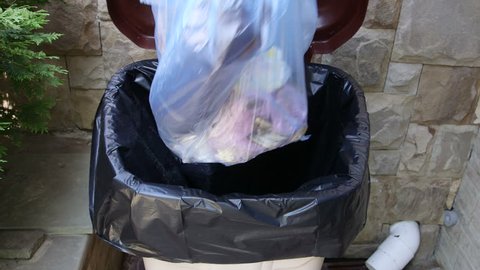 Hand putting plastic garbage bag into waste bin container