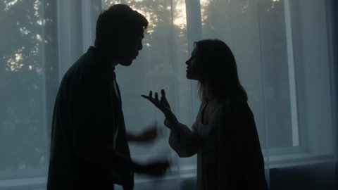 Silhouettes of man and woman shouting at each other, couple quarreling in the evening at home husband and wife screaming. Scandal and crisis in family. Domestic violence, abuse.
