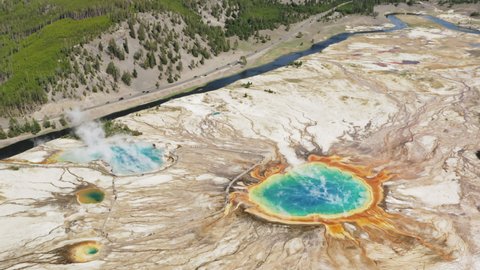 Helicopter aerial view of first American National park - Travel Yellowstone concept footage, 4K aerial. Tourists walking at steaming vibrant blue, green, teal, rainbow geyser lakes at Grand Prismatic