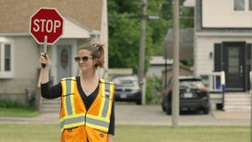 Crossing guard walks out into the intersection holding up sign - Powered by Shutterstock - Get 15% off with code: PIKWIZARD15