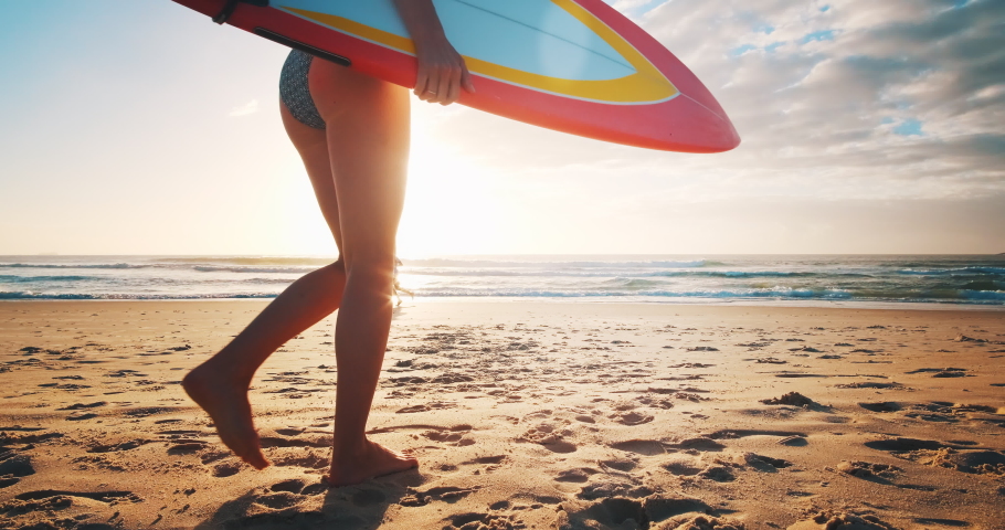 Female surfer. Young woman surfer runs with surfing board on the tropical beach at sunrise | Shutterstock HD Video #1076683055