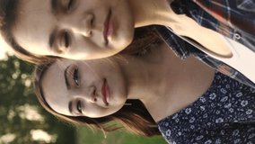Two young sisters look mysteriously into the camera lens. Vertical video.