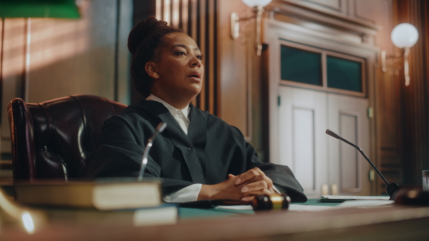 Court of Law Trial in Session: Portrait of Honorable Female Judge Reading Decision, striking Gavel. Presiding Justice Pronouncing Sentence. Guilty, Not Guilty Verdict Judgment. Cinematic Medium Shot Royalty-Free Stock Footage #1076688320