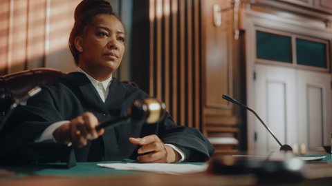 Court of Law Trial in Session: Portrait of Honorable Female Judge Reading Decision, striking Gavel. Presiding Justice Pronouncing Sentence. Guilty, Not Guilty Verdict Judgment. Cinematic Medium Shot