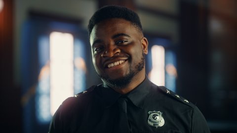 Authentic Portrait of Happy and Handsome Black Policeman in Universal Uniform Smiling at Camera. Successful African American Law Enforcement Agent. Courtroom Security Guard at Work. Cinematic Footage.