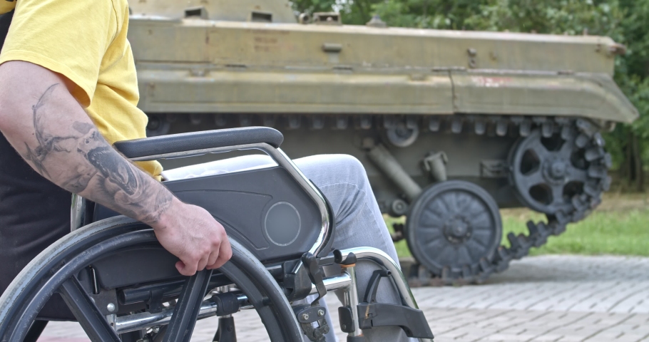 Young man in wheelchair near tank outdoors