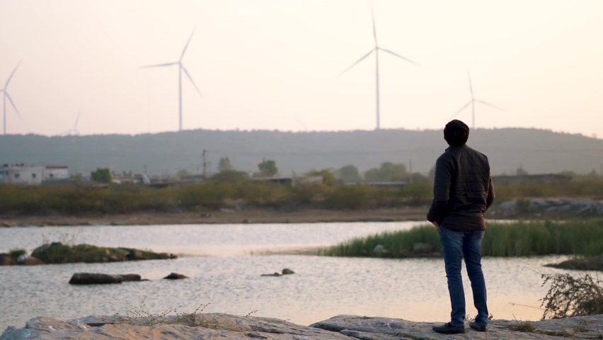 Indian man looking at the windmills during the sunset at Wankaner, Gujarat, India | Shutterstock HD Video #1076696819