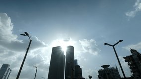 A silhouette of two high rises office buildings with the sun rays popping between them. a 4K video clip, Tel Aviv, Israel.