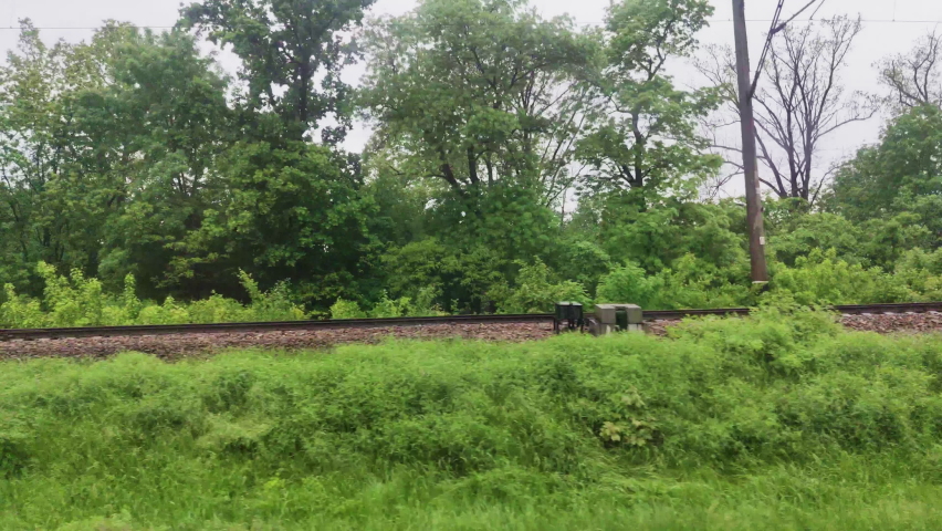 View from window of speed train on landscape of beautiful nature field road with forest. Fast moving between trees. Royalty-Free Stock Footage #1076699807