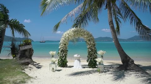 Beautiful Wedding event decoration beach sea tropical island sunset. Set up arch decor flowers pattern coconut palm trees sand sunlight. Setting outdoor marriage detail table stage sky clouds. space 