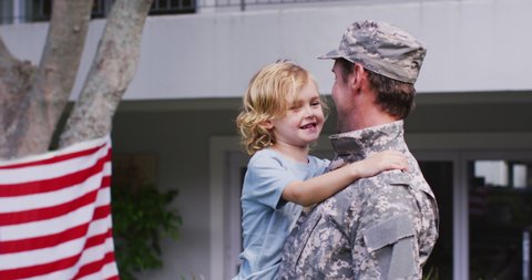 Caucasian military dad in uniform picking up his son in the garden. veteran soldier returning home concept